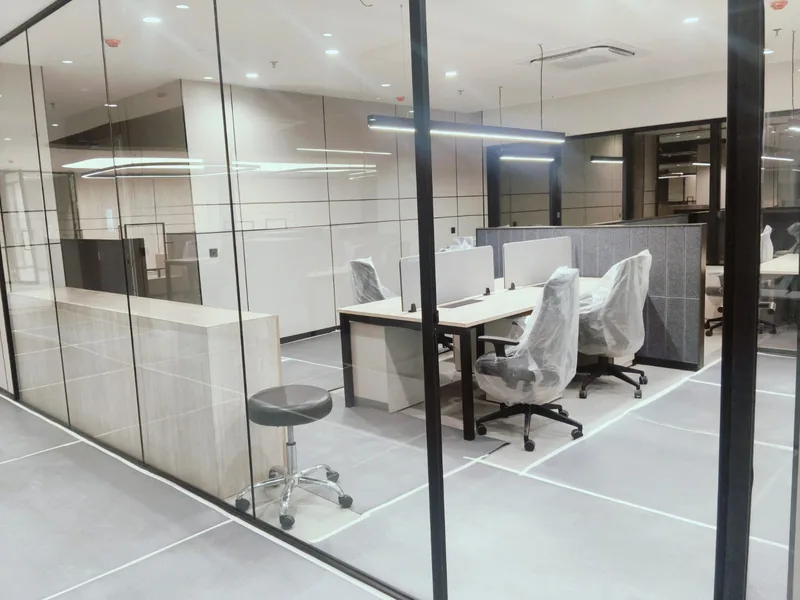 Glass-partitioned office cabin with ceiling cassette air conditioner and pendant linear lighting