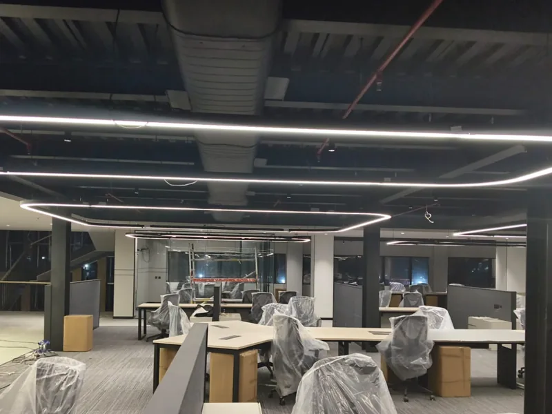 Spiral ducting, fire-fighting pipework and continuous LED lighting in the exposed ceiling over office workstations