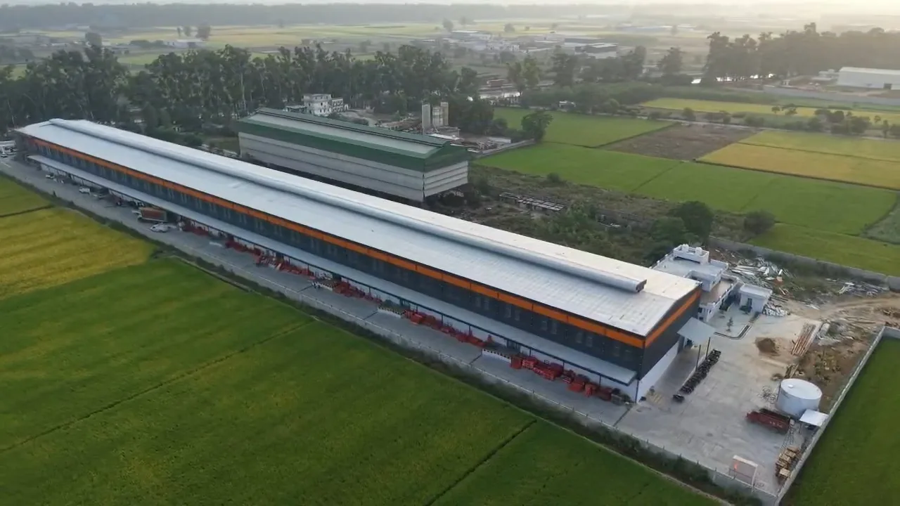 Aerial view along the loading-dock face of the SBJ Nirmal warehouse with parts staged at the bays